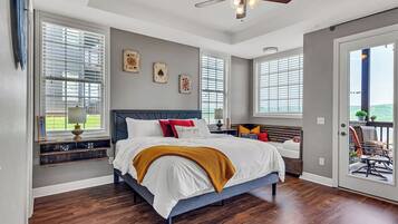 A bedroom with a bed, a ceiling fan, and a view through a door.