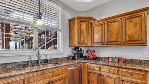 A kitchen with wooden cabinets, granite countertops, a dishwasher, and a window with blinds. - Stay & Play! Right next to SDC + Waffles, Games, Hottub, Pool, Outdoor Movies! (Branson)