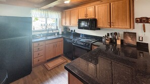 A kitchen with wooden cabinets, a black refrigerator, a stove, and a microwave. - Summit Sanctuary of MeadowRidge. Great space and great location! (Fraser)