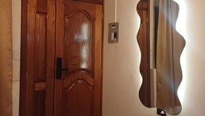 A room with a wooden door, a light switch, and a wall-mounted mirror. - Safe and relaxed apartment 10 minutes from Cuenca's city center (Cuenca)