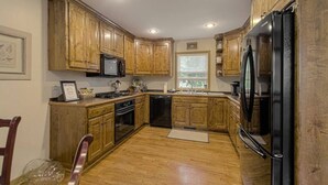 A kitchen with wooden cabinets, a refrigerator, a microwave, and a dishwasher.