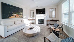 A modern living room with a white sofa, a round coffee table, and a fireplace.