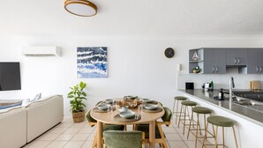 Een moderne keuken met grijze kastjes, een roestvrijstalen spoelbak en een eethoek met een ronde tafel gedekt voor vier personen.