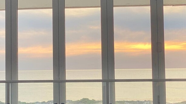 Udsigt gennem et vindue ud til havet og en overskyet himmel.