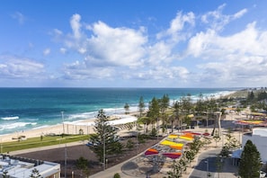 A coastal view with a beach, a clear sky, and a parking area with colorful umbrellas. - Renovated Ocean-View Scarborough Apartment | Walk to Beach & Amphitheatre (Scarborough)