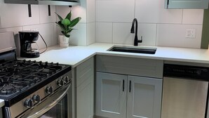 Una cocina moderna con armarios grises, una estufa de acero inoxidable, un microondas y un lavavajillas.