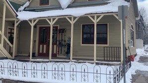 Una casa de dos pisos con un porche cubierto y un tejado cubierto de nieve.