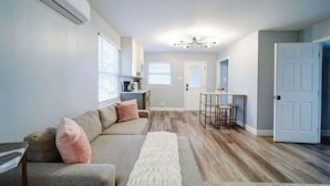 A modern living room with a sofa, a coffee table, and a dining area with a table and chairs.