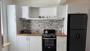 A modern kitchen with white cabinets, a black stove, and a black refrigerator. - Fantastic 2-bedroom apartment with AC in charming Sosúa (Sosúa)