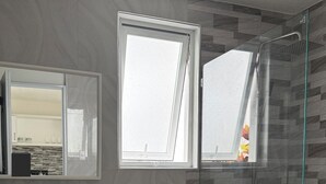 A modern bathroom with a toilet, sink, and shower. There are two windows providing natural light. - Fantastic 2-bedroom apartment with AC in charming Sosúa (Sosúa)