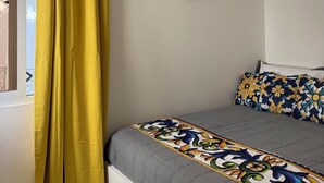 A bedroom with a bed, a ceiling fan, and a window with yellow curtains. - Fantastic 2-bedroom apartment with AC in charming Sosúa (Sosúa)