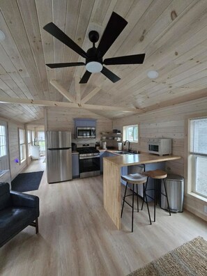A modern kitchen with a central island, stainless steel appliances, and a ceiling fan.