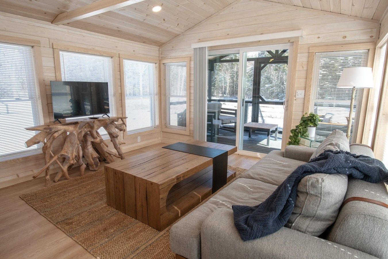 Un interior moderno con techo de madera, una amplia mesa de centro de madera, un sofá y un televisor.
