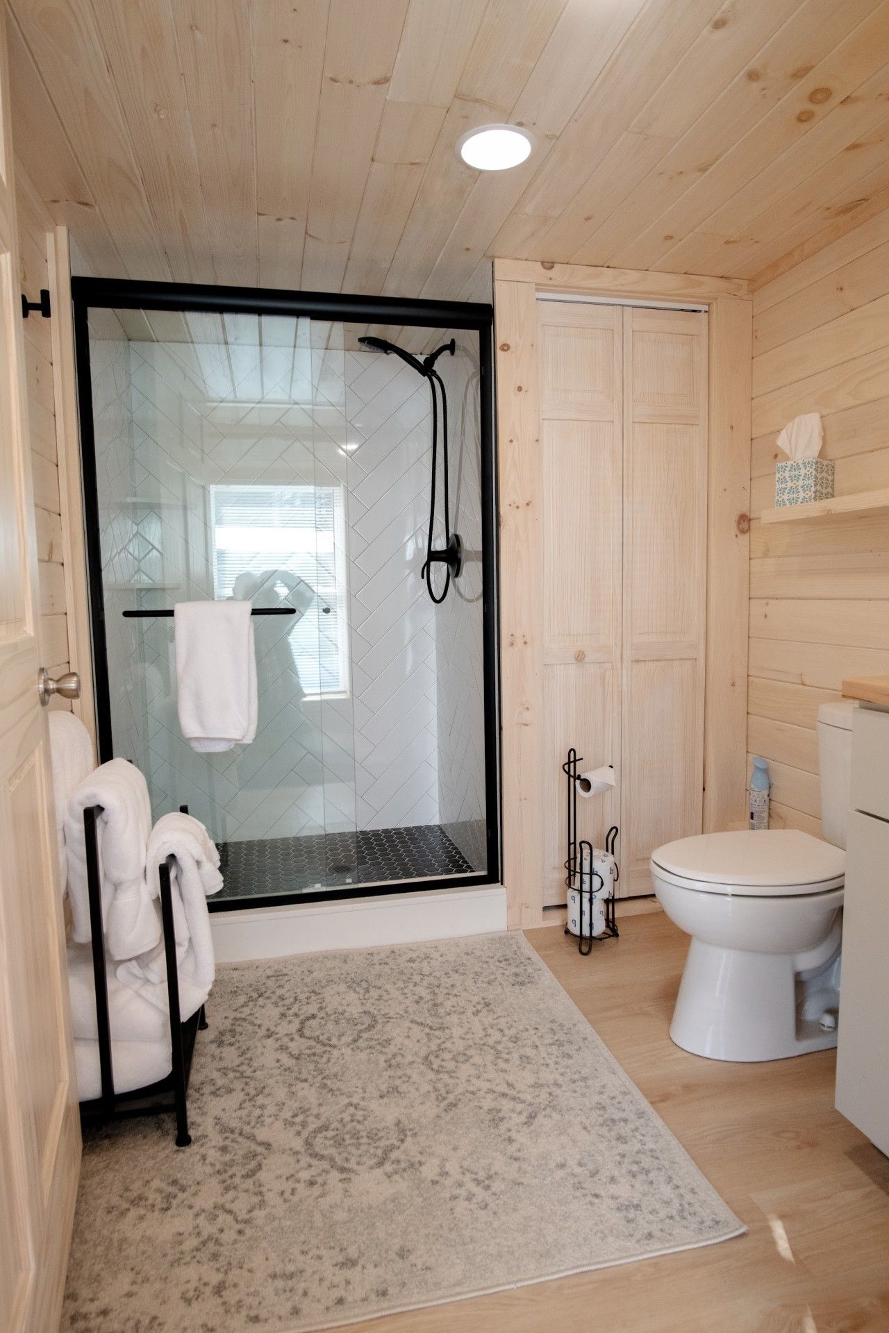 A bathroom with a glass-enclosed shower, a toilet, and a towel rack.