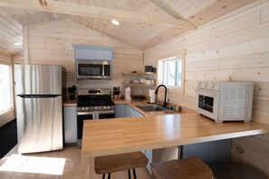 Eine kleine Küche mit Kühlschrank, Herd, Mikrowelle und Backofen.
