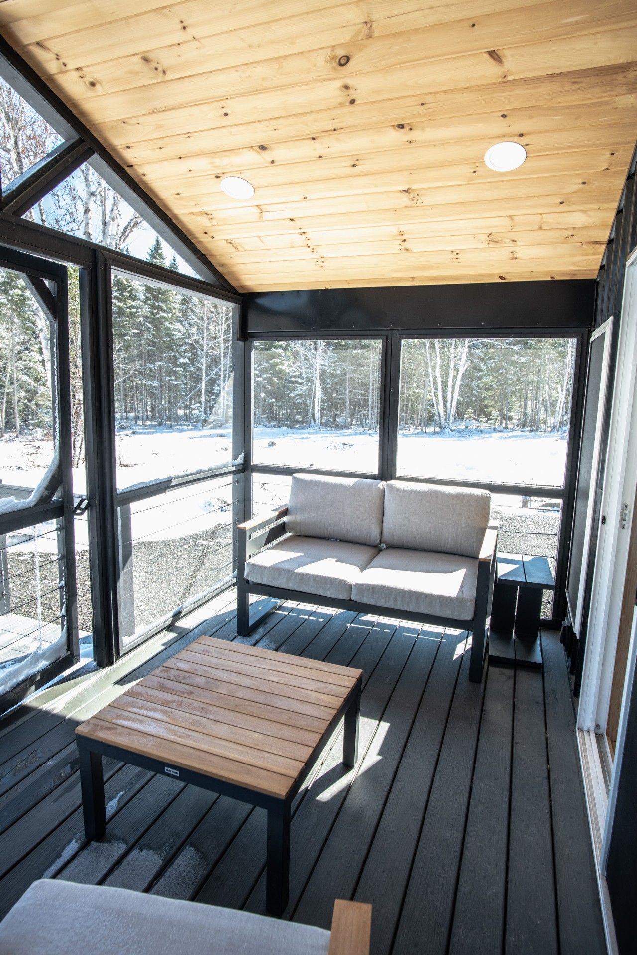A covered outdoor area with a wooden bench, a sofa, and a table.