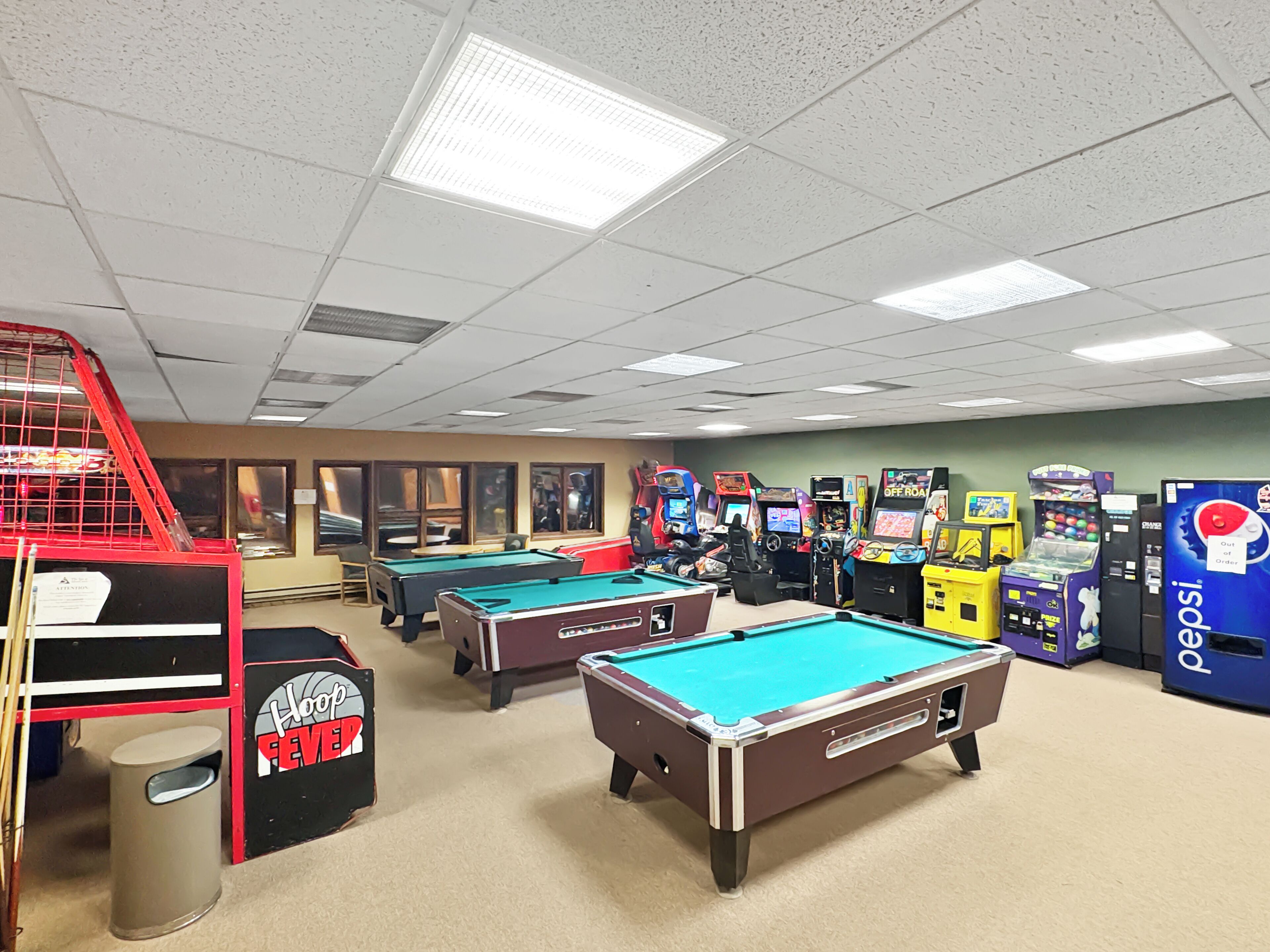 A recreational area with pool tables, arcade games, and a red climbing structure.