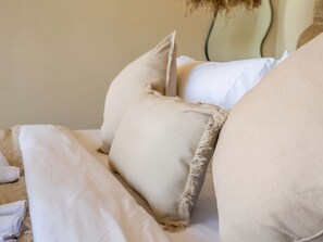 A bed with white bedding and a beige pillow. - Kaktus Villa Pererenan | Luxury 1BR Private Pool Villa (Badung Regency)