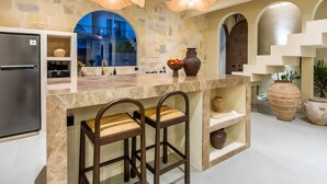 Una cocina moderna con protector mural de piedra, refrigerador de acero inoxidable y dos taburetes de bar.
