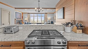 Una cucina moderna con piano cottura in acciaio inossidabile, ripiani in granito e rivestimenti in legno.