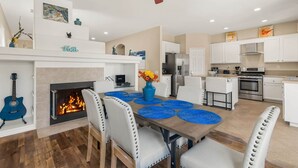 A modern kitchen with white cabinets, a built-in oven, and a dining area with a fireplace.
