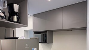 A modern kitchen with a stainless steel refrigerator, a microwave, and a gas stove. - Apart Hotel recém reformado TV de cinema (Salvador)