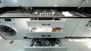 A modern kitchen with a built-in washing machine, stainless steel appliances, and ample storage drawers.