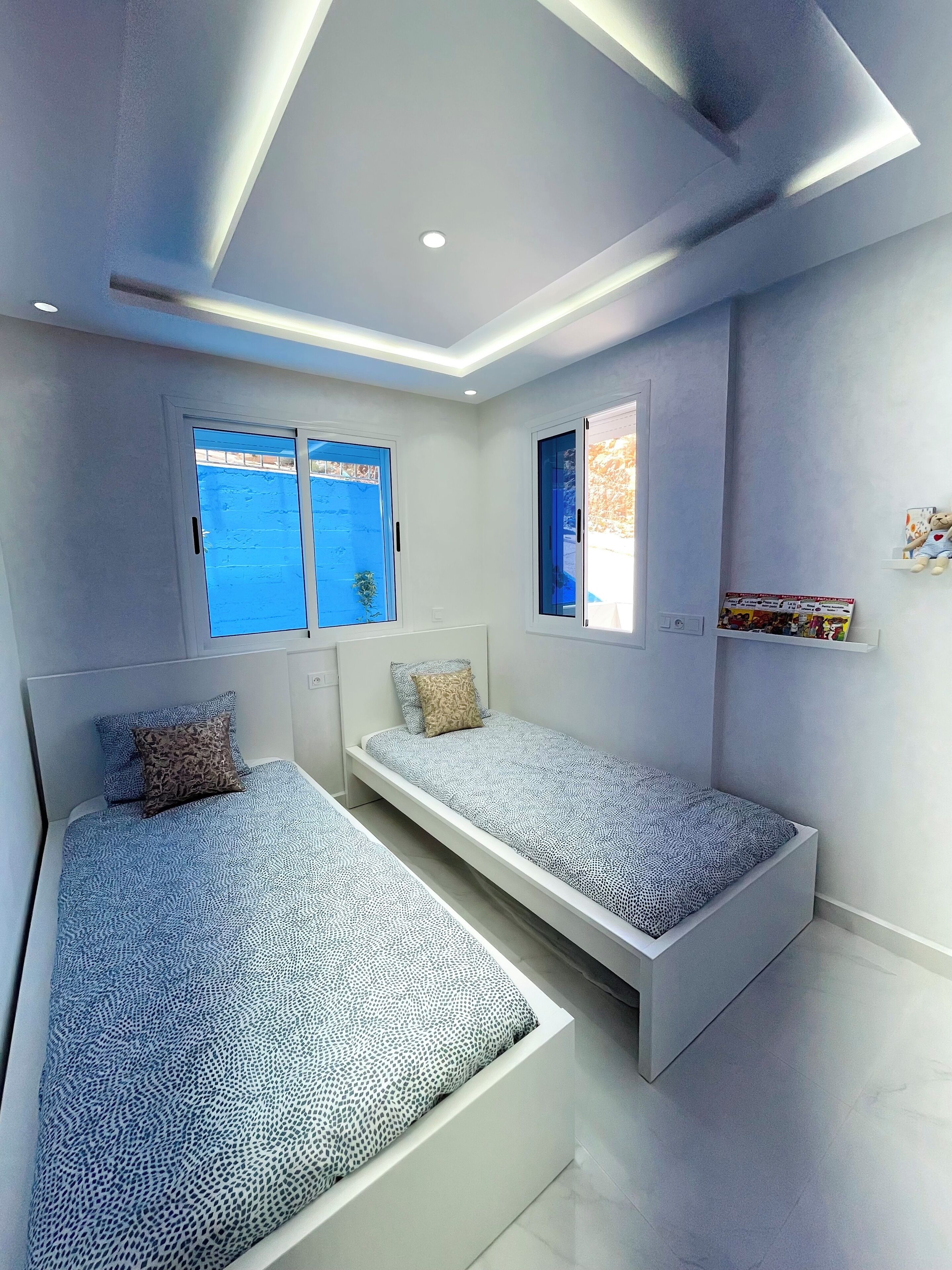Un dormitorio moderno con dos camas, un tragaluz y vista al mar.