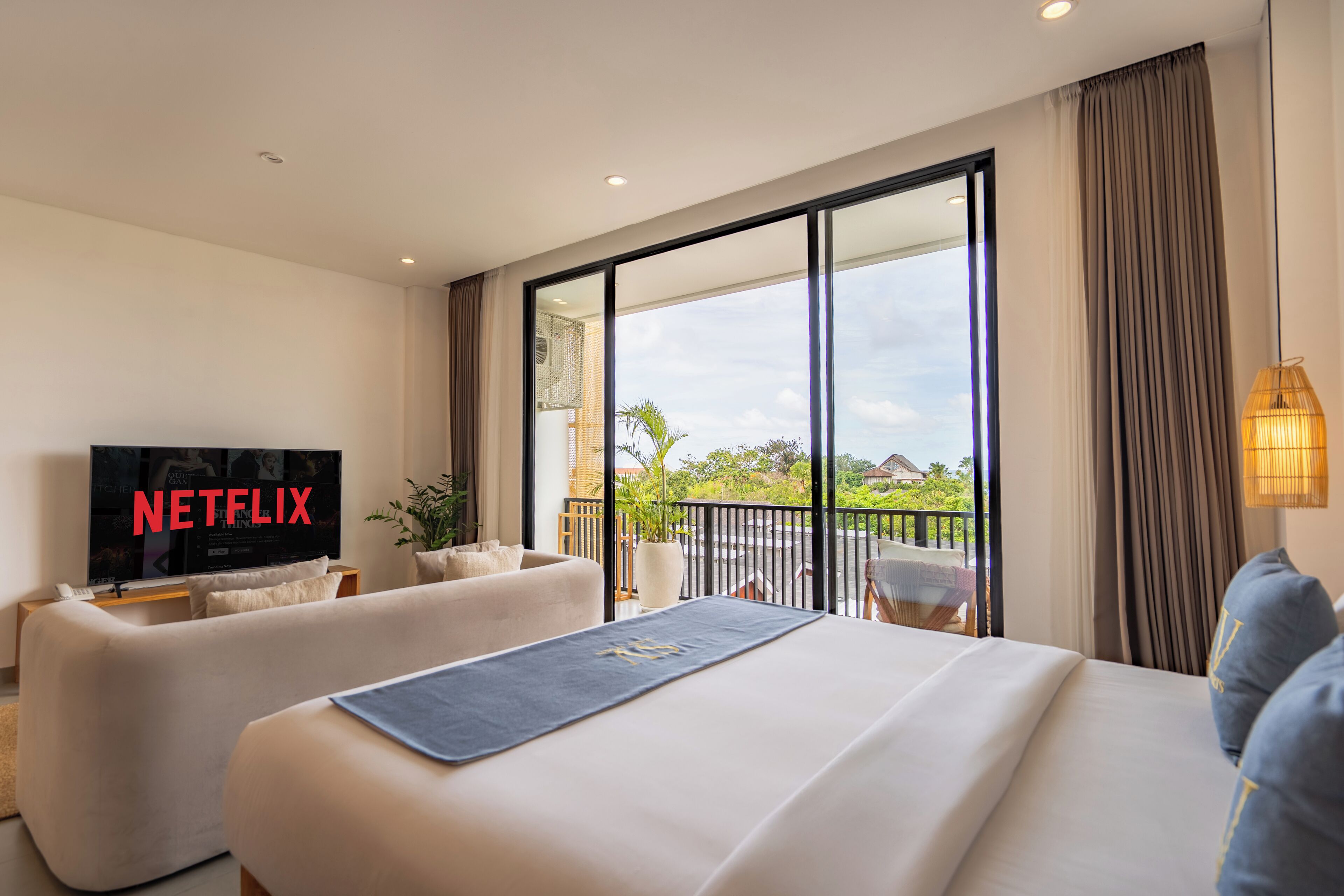 Una habitación de hotel moderna con una cama grande, un sofá, un televisor y un balcón con vistas.