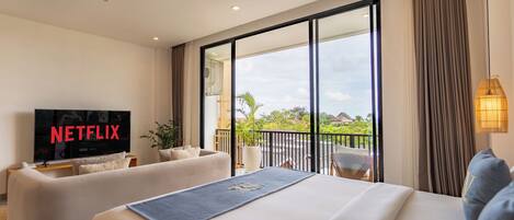 Una habitación de hotel moderna con una cama grande, un sofá, un televisor y un balcón con vistas.