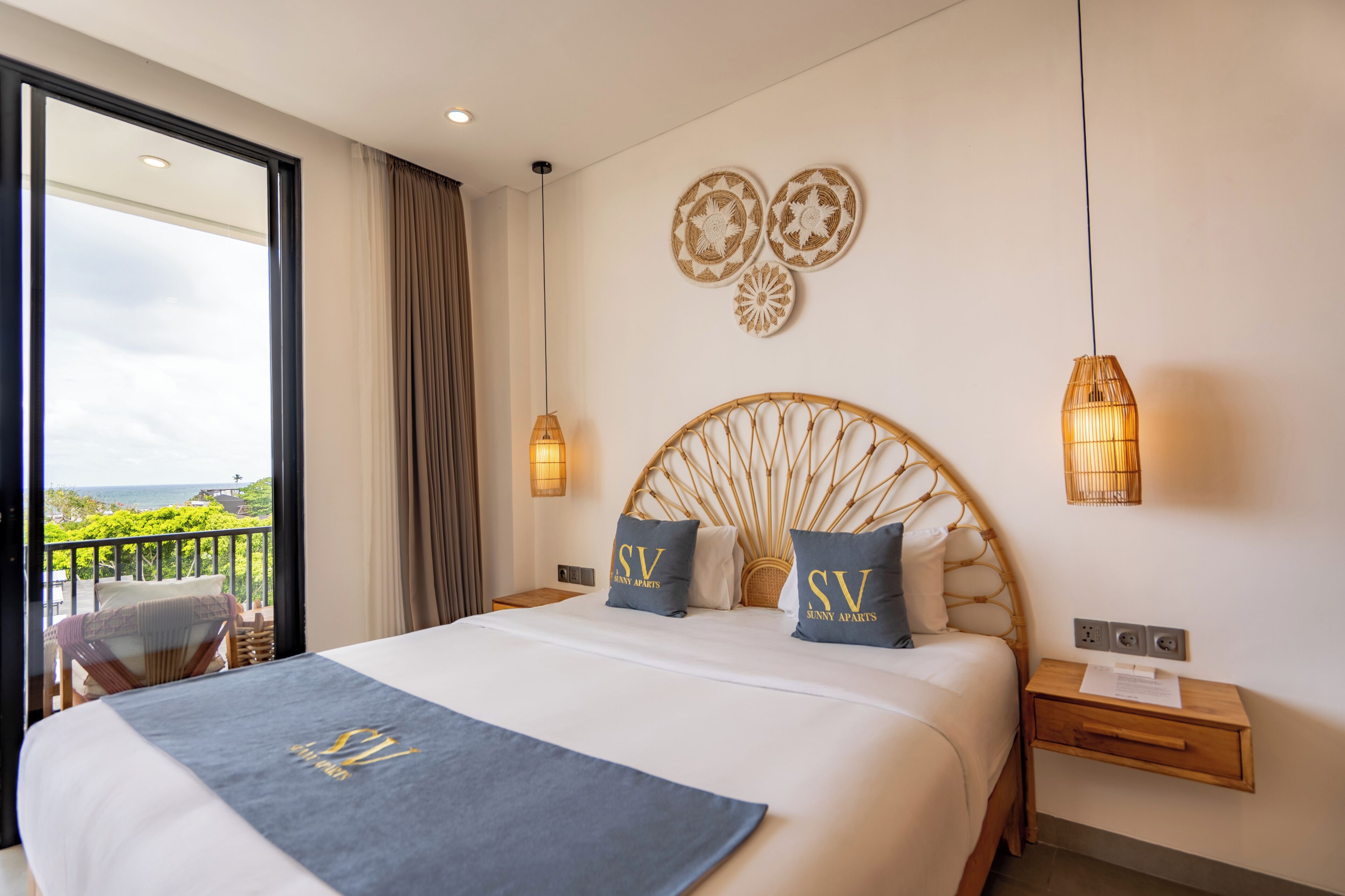 Habitación de hotel con una cama grande, vista al mar y un balcón.