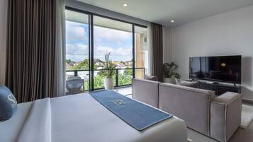 Una habitación de hotel moderna con una cama grande, un televisor de pantalla plana, un balcón con vistas a la ciudad y una zona de estar con una planta.