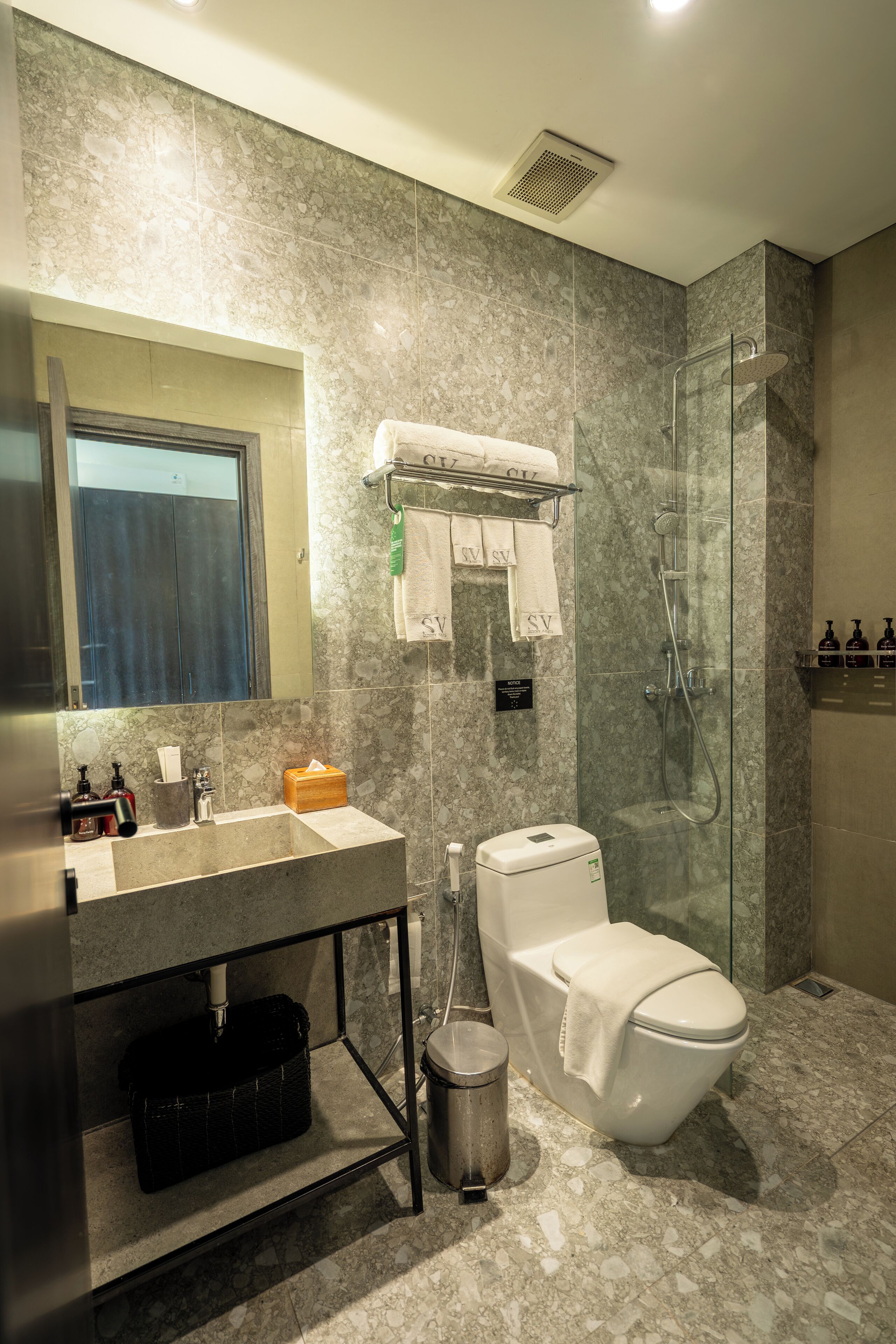 A modern bathroom with a marble sink, a glass-enclosed shower, and a toilet.