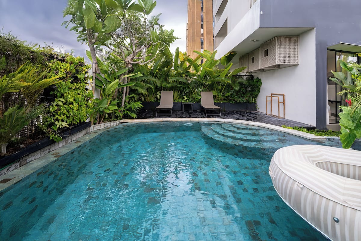 A swimming pool with lounge chairs and potted plants around it.