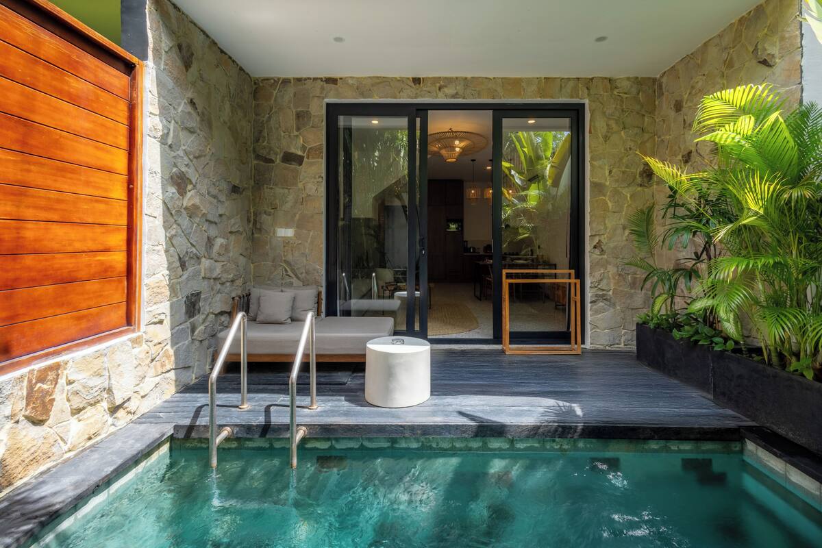 A swimming pool with a glass enclosure, a wooden deck, and a stone wall.