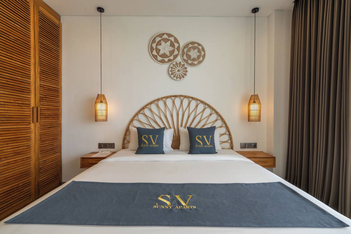 A hotel room with a large bed, two bedside tables, a headboard with a circular design, and wall decor.