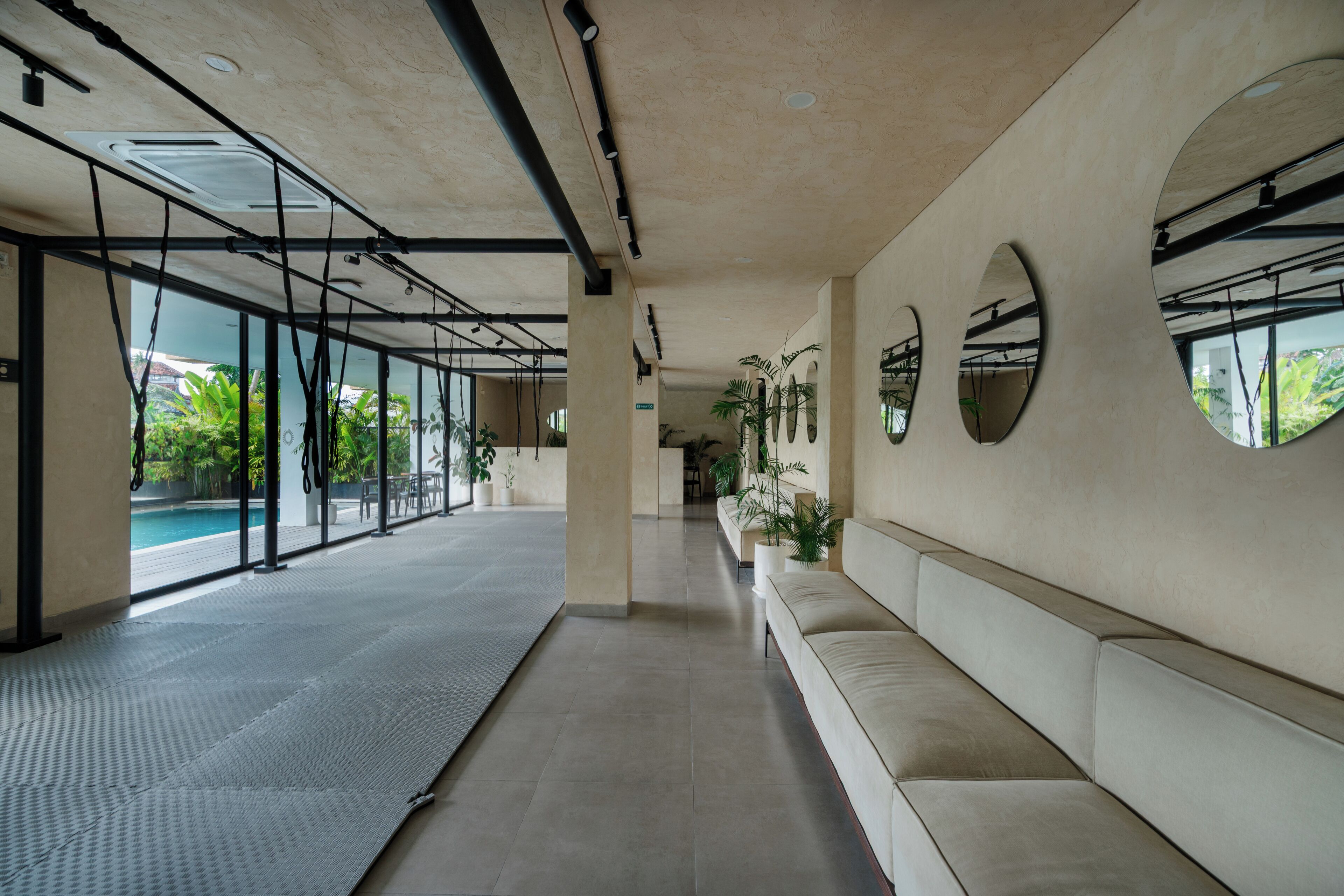 A corridor with a pool, seating area, and large windows.