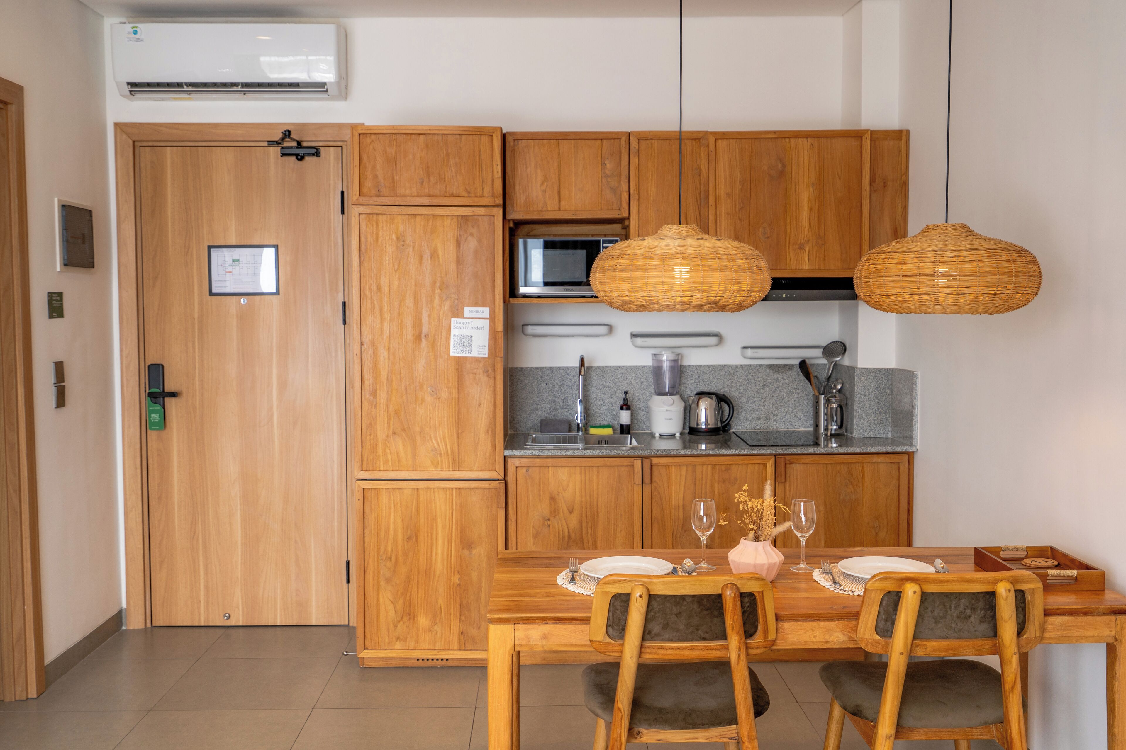 A compact kitchen with wooden cabinets, a microwave, and a dining area with a table set for two.