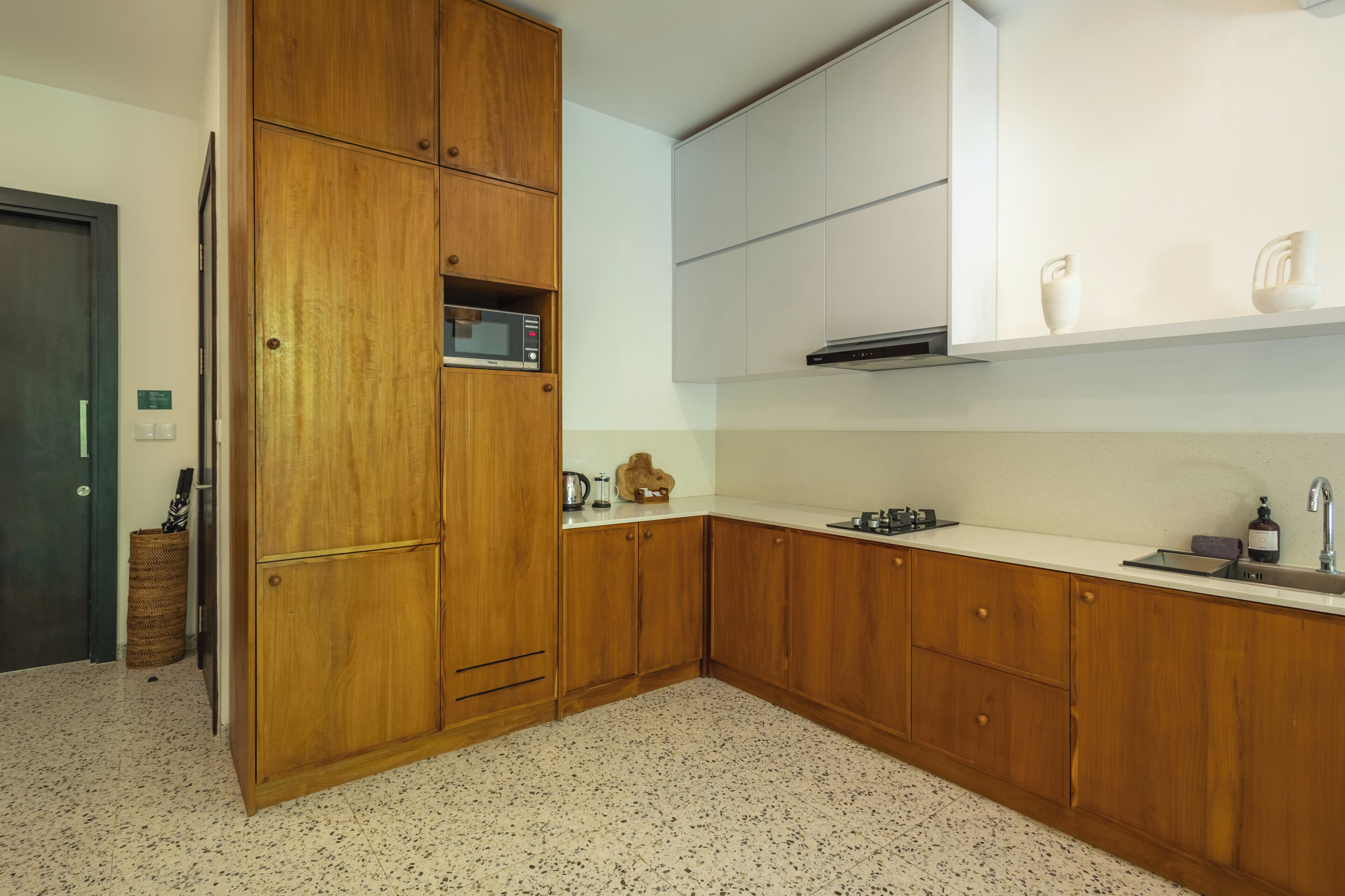 Une cuisine avec des meubles de rangement en bois, un four à micro-ondes et un évier.