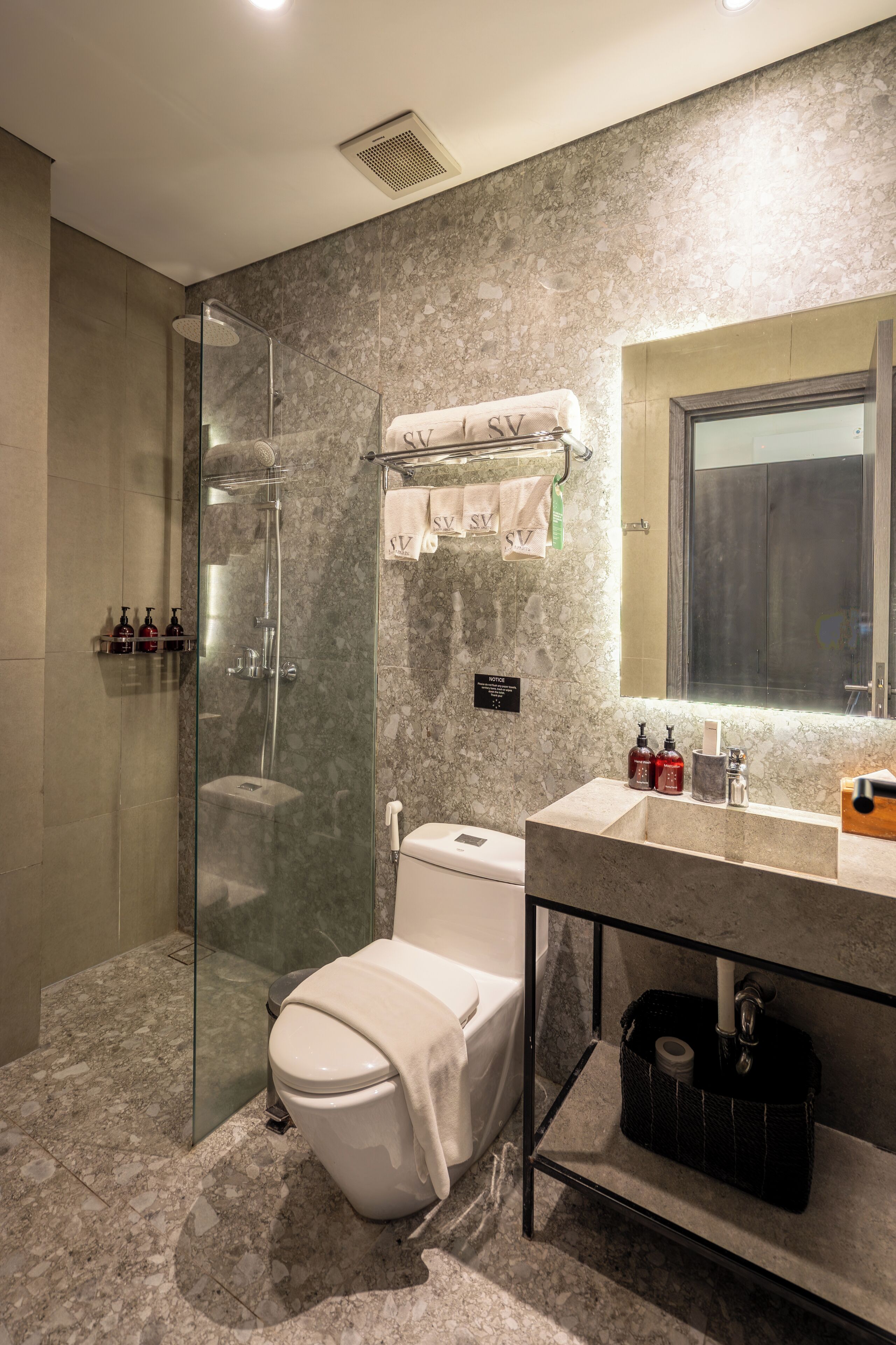 A modern bathroom with a glass-enclosed shower, a toilet, and a vanity with a mirror.