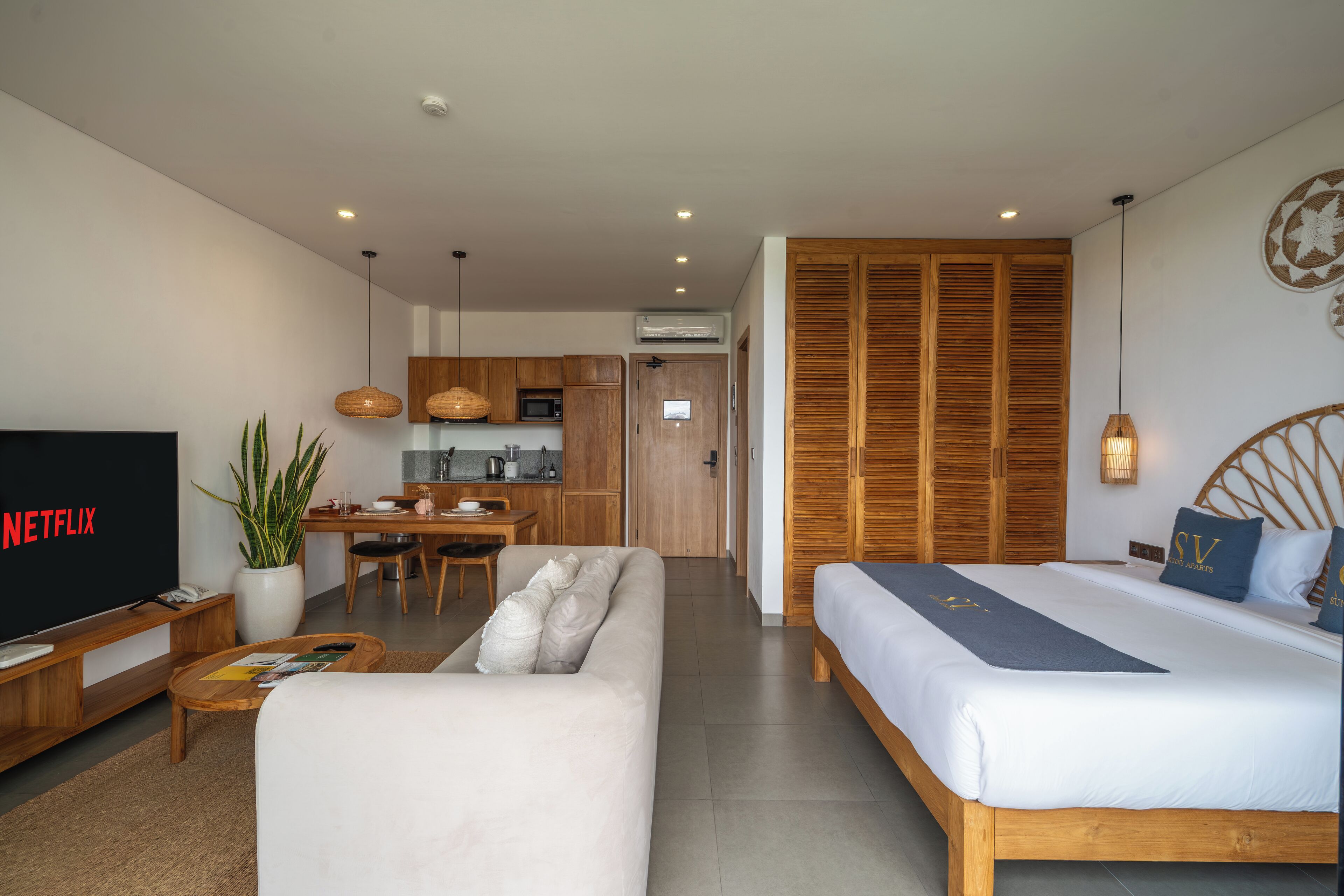 Une chambre d’hôtel moderne équipée d’un canapé, d’un lit, d’une télévision, d’un coin repas et d’une cuisine.