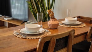 A dining table set with white bowls, a vase with dried flowers, and a glass of water. - Sunny Aparts 1 by Betterplace (Tibubeneng)