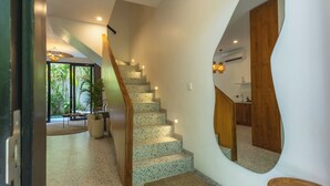 A modern interior with a spiral staircase, a large mirror, and a view of a balcony with plants. - Sunny Aparts 1 by Betterplace (Tibubeneng)