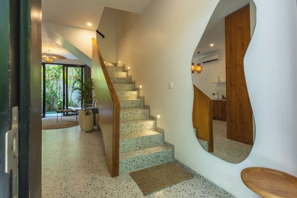 A modern interior with a spiral staircase, a large mirror, and a view of a balcony with plants. - Sunny Aparts 1 by Betterplace (Tibubeneng)