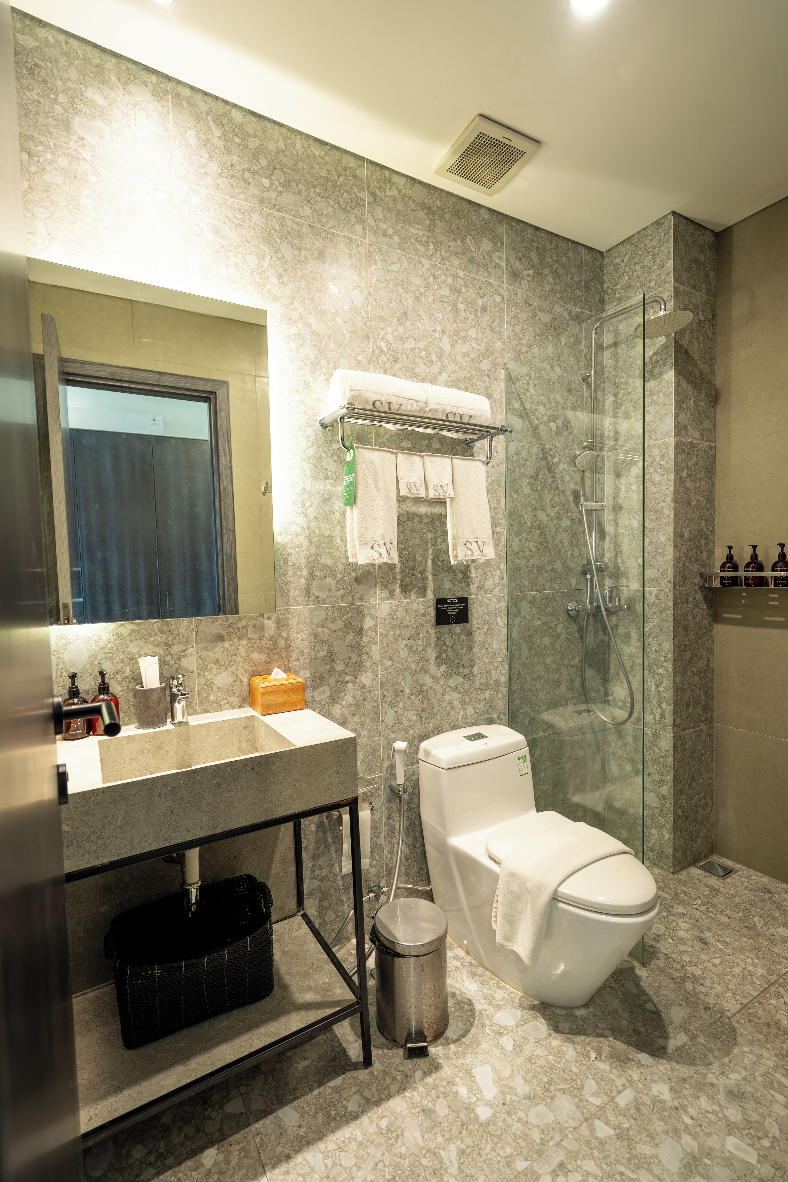 Een moderne badkamer met een marmeren wastafel, een douche met glazen wanden en een toilet.