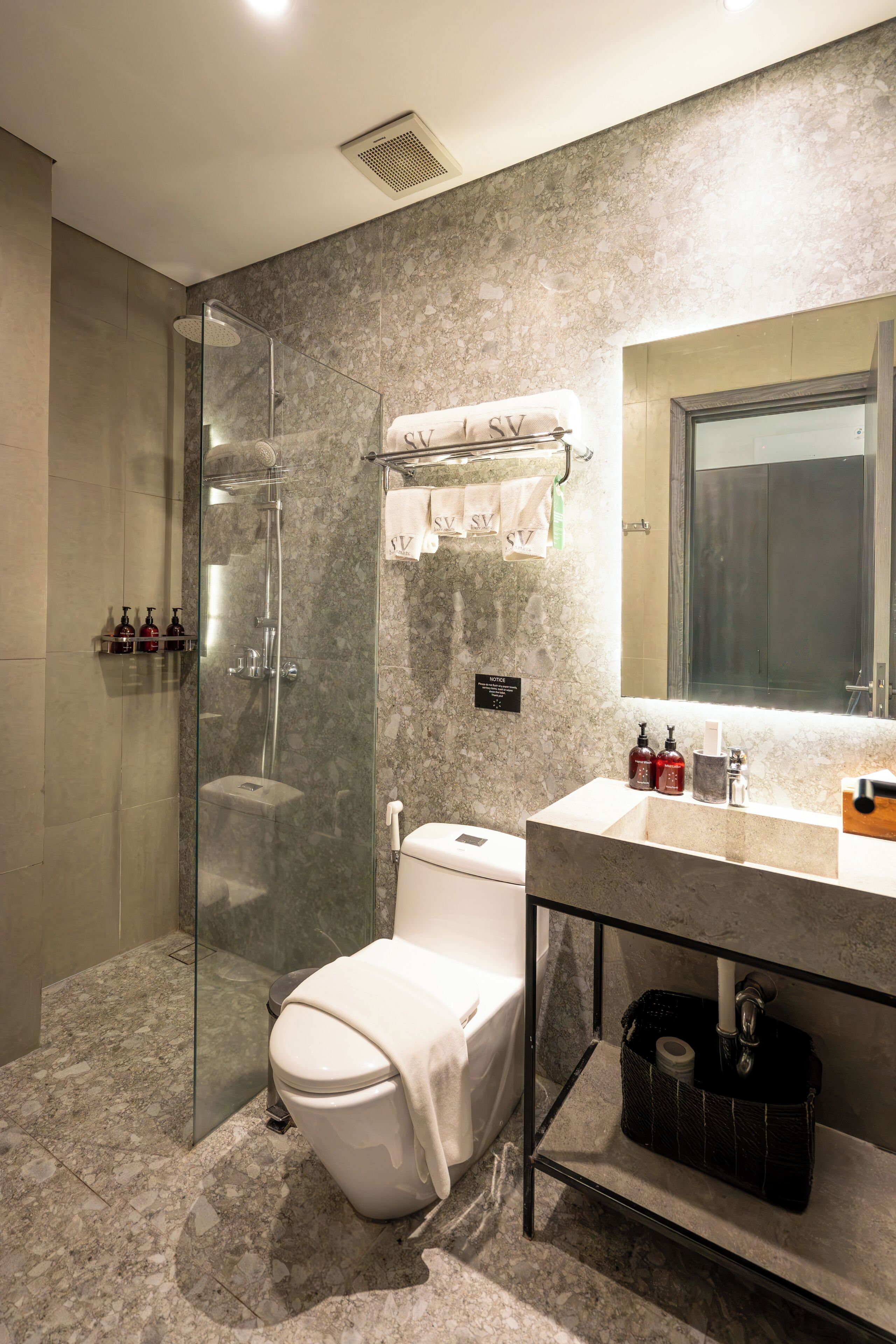 A modern bathroom with a glass-enclosed shower, a toilet, and a vanity with a mirror.