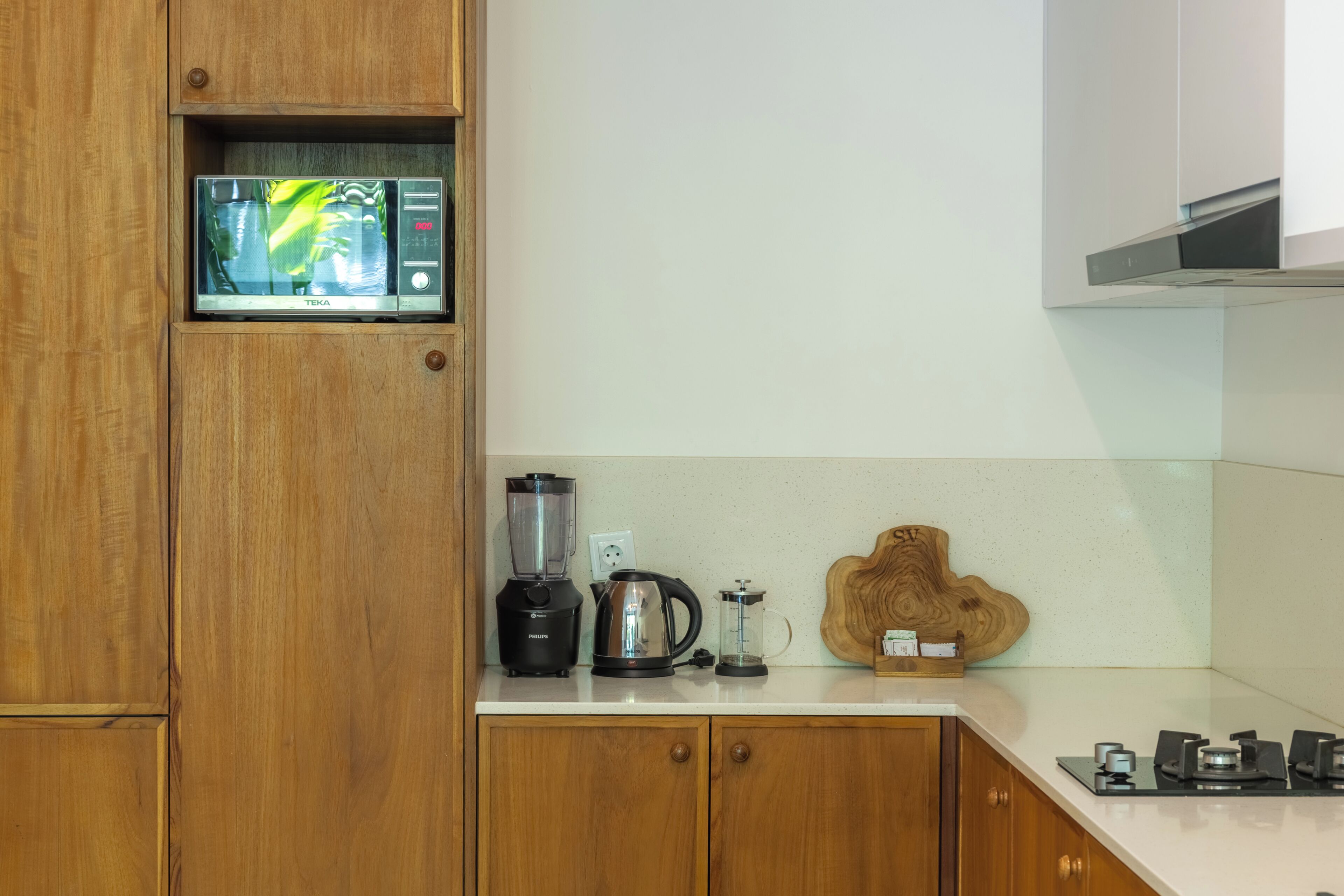 A kitchen with wooden cabinets, a blender, a kettle, and a coffee maker on the countertop.