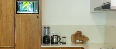 Een keuken met houten kastjes, een blender, een waterkoker en een koffiezetapparaat op het aanrecht.