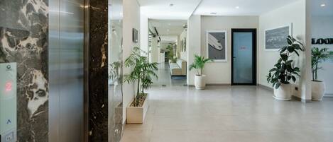A modern hotel lobby with a marble reception desk, a reception area, and a 'Staff Only' door.