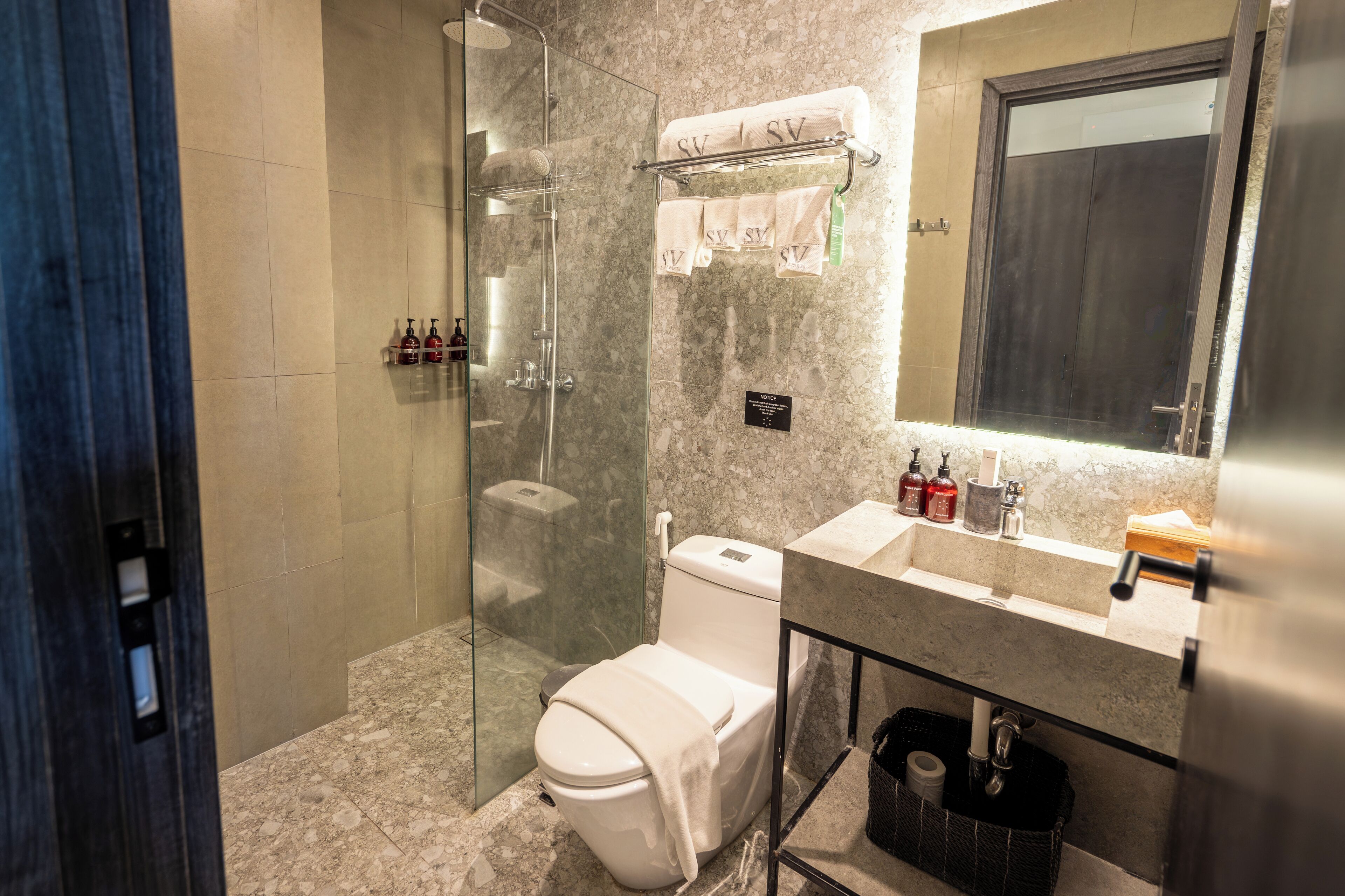 A modern bathroom with a glass-enclosed shower, a toilet, and a sink with toiletries.